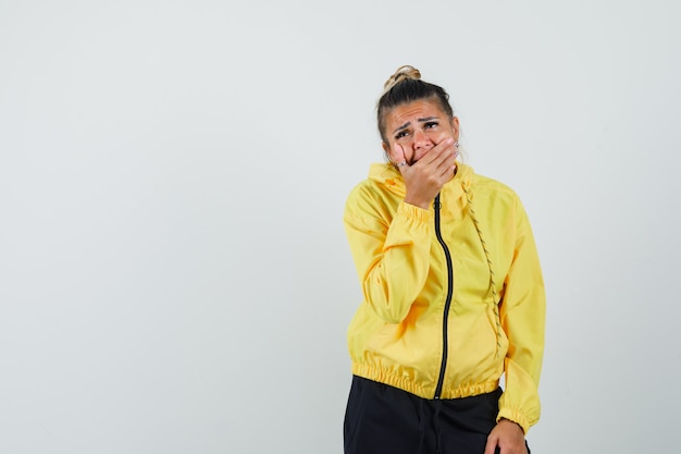 Woman holding hand on mouth in sport suit and looking depressed , front view.