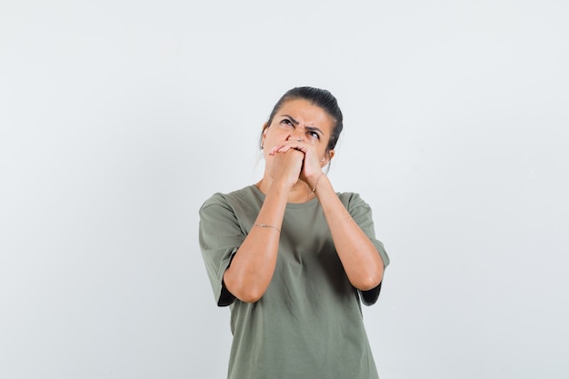 woman holding hands clasped in t-shirt and looking hesitant