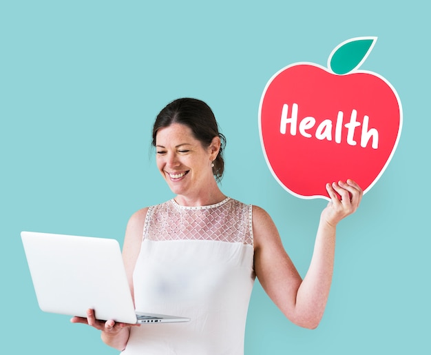 Free Photo woman holding a health icon and using a laptop