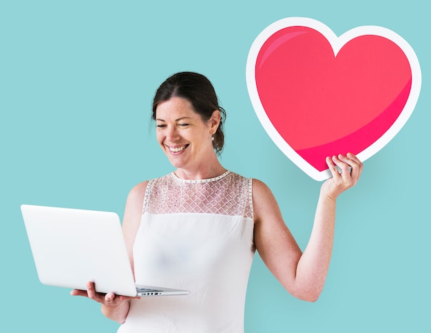 Free photo woman holding a heart emoticon and a laptop