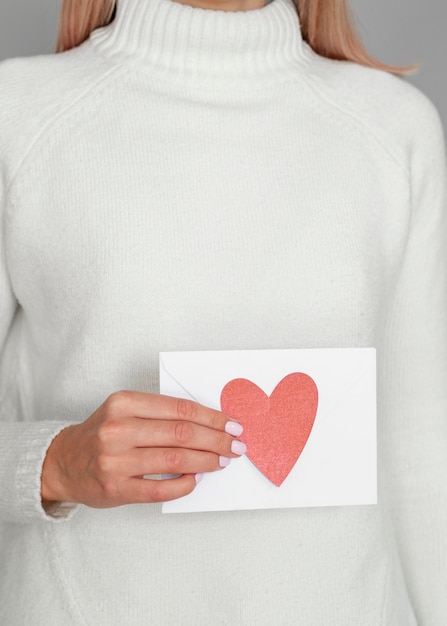 Free photo woman holding heart envelope studio shot