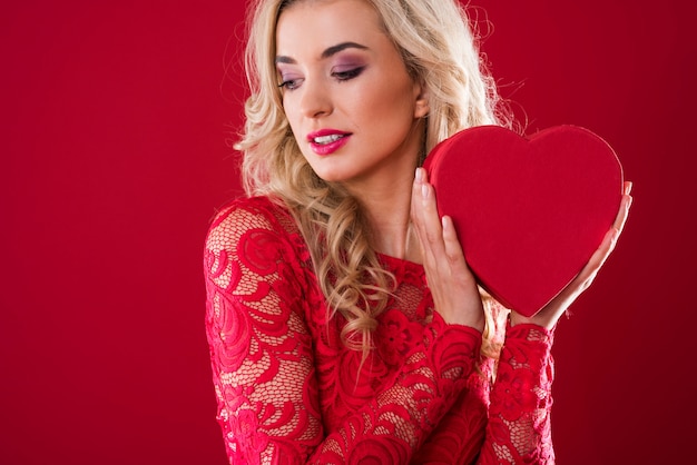 Woman holding heartshape box next to her face