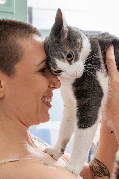 Free photo woman holding her adorable kitty at home