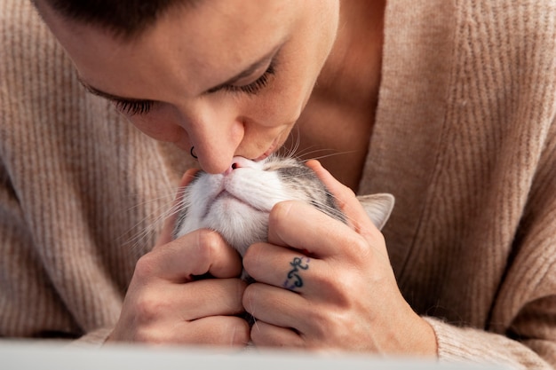 Free photo woman holding her adorable kitty at home