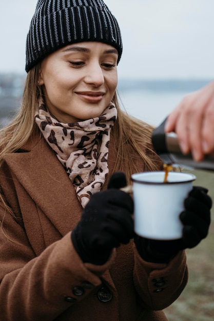 Free Photo woman holding her cup to get a warm drink outdoors