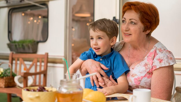 Woman holding her grandson next to a caravan