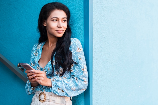 Free photo woman holding her phone and looking away