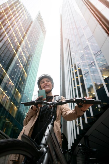 Woman holding her smartphone and walking by her bike