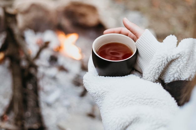 Free Photo woman holding a hot cup of tea outdoors