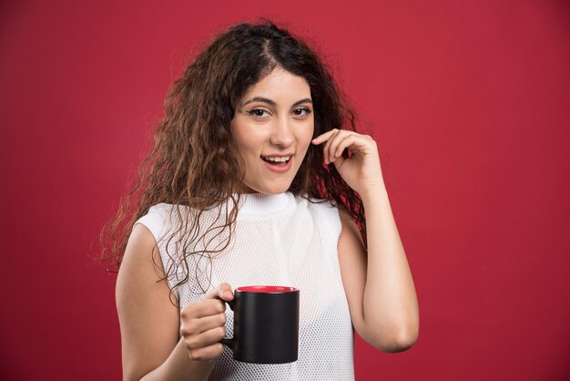 Woman holding hot dark cup on red