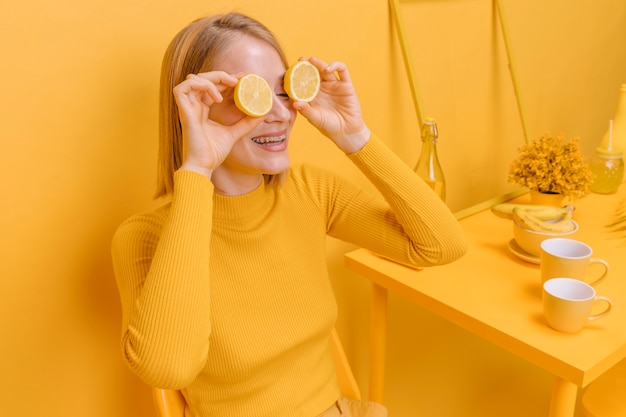 Free photo woman holding lemons in front of eyes in a yellow scene