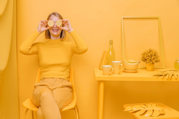 Free photo woman holding lemons in front of eyes in a yellow scene