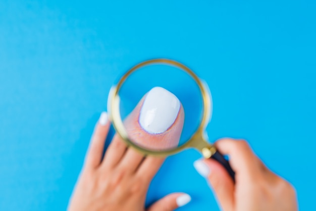 Free Photo woman holding magnifying glass over nail