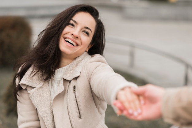 Free Photo woman holding man's hand outdoors