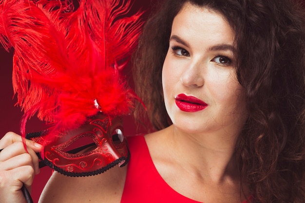 Woman holding mask with red feathers