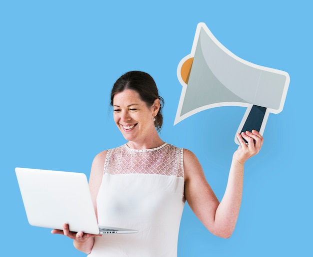 Free Photo woman holding a megaphone icon and using a laptop