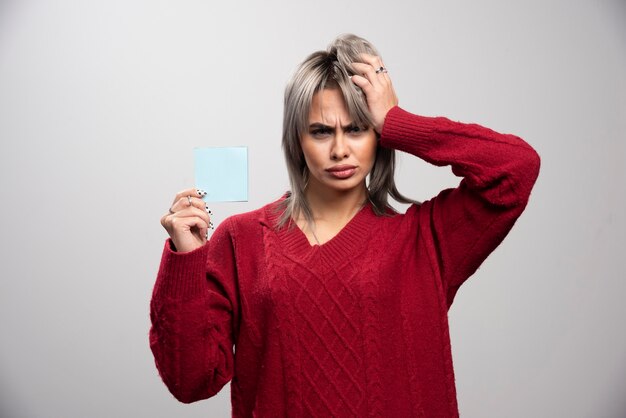 Woman holding memo pad and thinking about job.