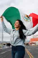 Free photo woman holding mexican flag in the street