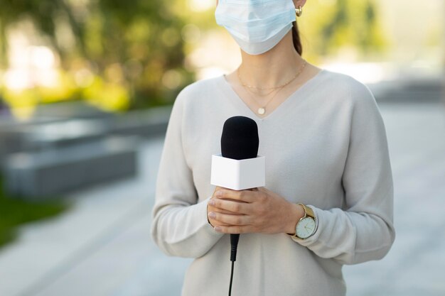 Woman holding a microphone while wearing a medical mask