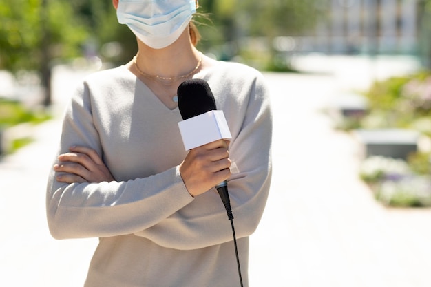 Woman holding a microphone while wearing a medical mask