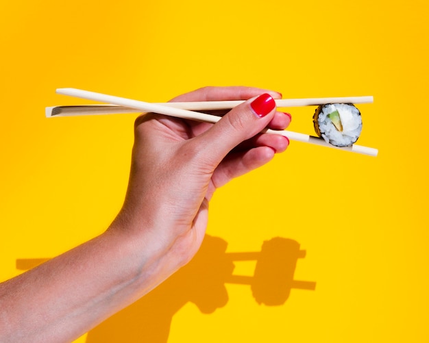 Free Photo woman holding a nigiri on a yellow background