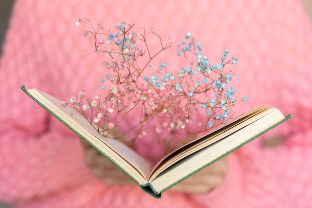 Woman holding an open book with a bouquet of dried flowers inside