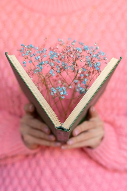 Woman holding an open book with a bouquet of dried flowers inside