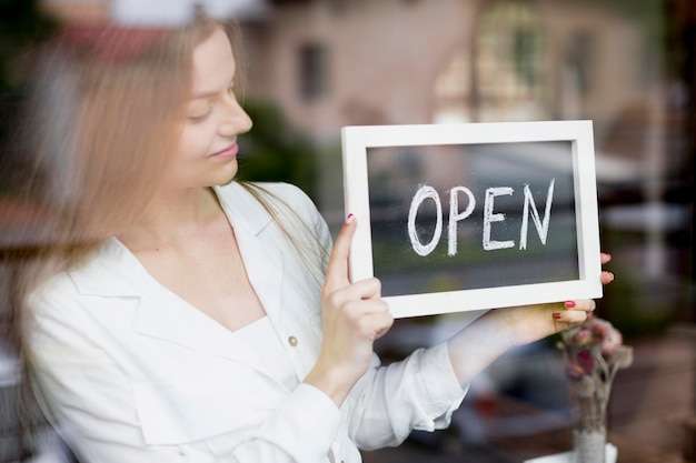 Woman holding open sign in coffee shop window