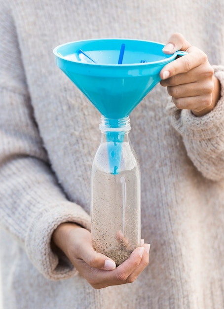 Free Photo woman holding plastic bottle with funnel