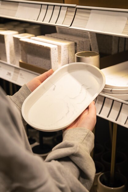 Woman holding a plate in the store the concept of choosing dishes