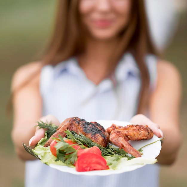 Woman holding plate with barbecue outdoors