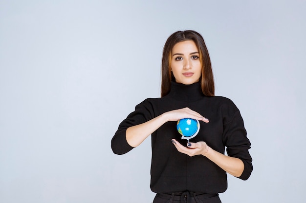 woman holding and promoting a mini globe.