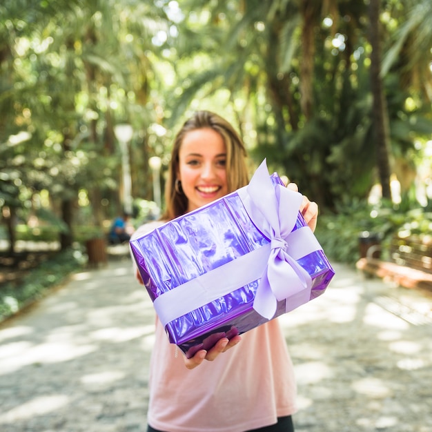 Free Photo woman holding purple gift box in park