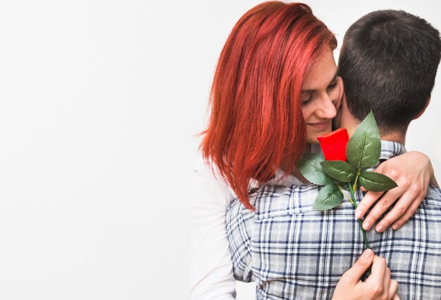 Free Photo woman holding red rose hugging her husband