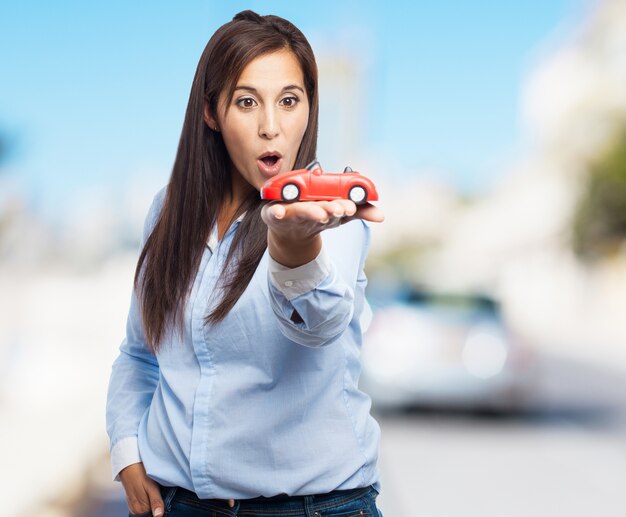 Woman holding a red toy car with blurred background