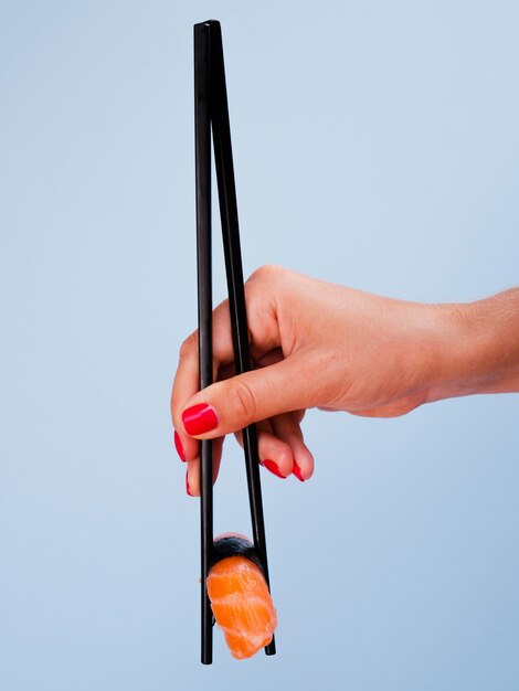 Woman holding a salmon sushi on a blue background