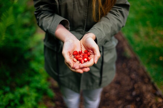 Woman holding several small strawberries in her hands