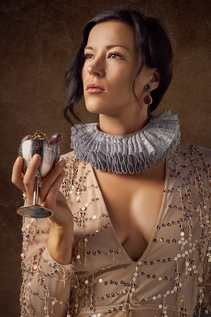 Woman holding silver wine glass with purple grapes 