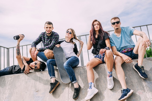 Free photo woman holding skateboard sitting with friends on ramp