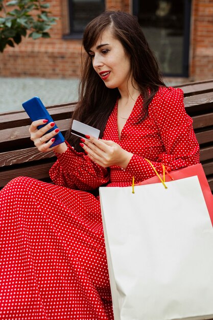 Woman holding smartphone and credit card purchasing online during sales