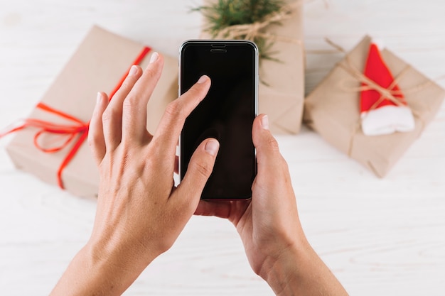 Woman holding smartphone in front of gift boxes