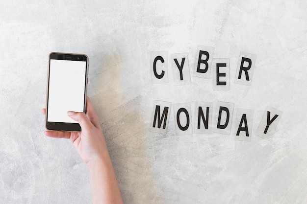 Free Photo woman holding smartphone near cyber monday inscription 