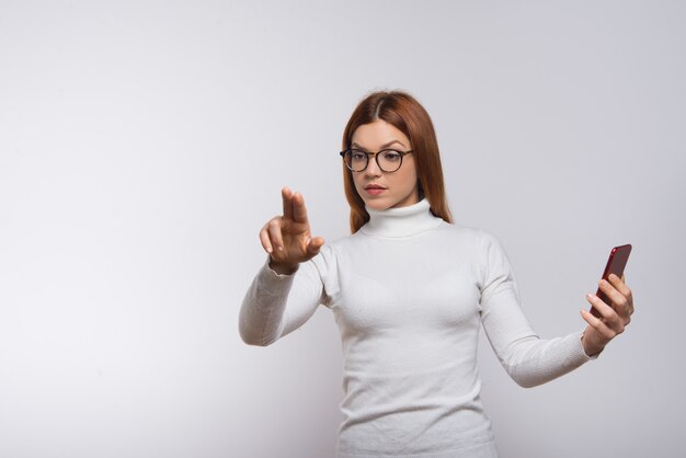 Woman holding smartphone and pushing virtual button