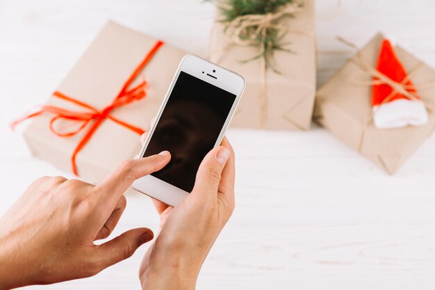 Woman holding smartphone above small gift boxes