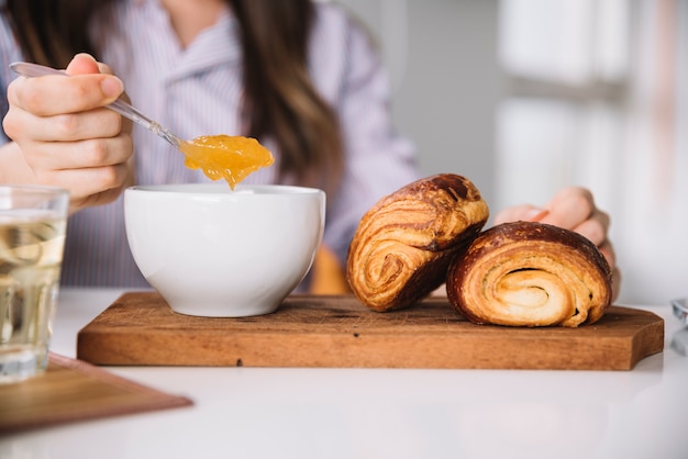 Free photo woman holding spoon with jam near buns