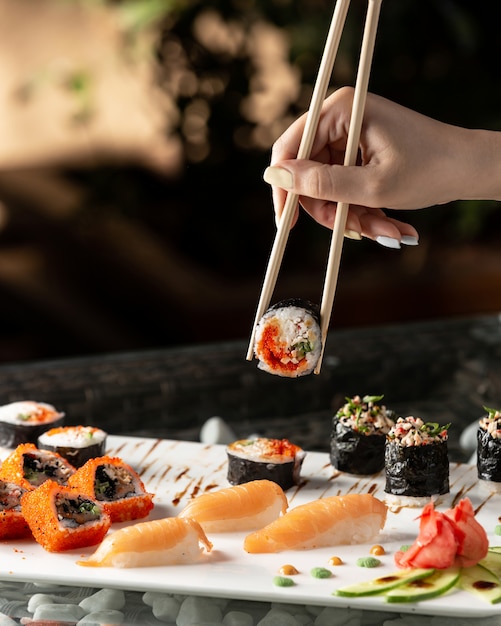 Free Photo woman holding sushi roll with chopsticks