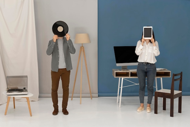 Free Photo woman holding tablet and man holding vinyl