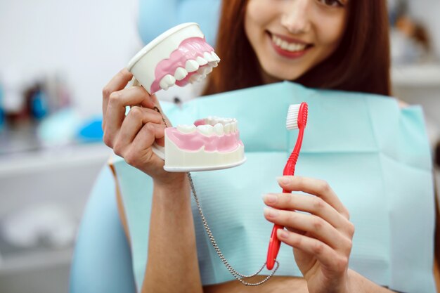 Woman holding a toothbrush and a dental mold