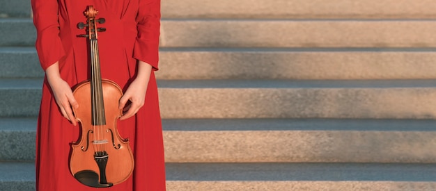 Free photo woman holding violin next to steps