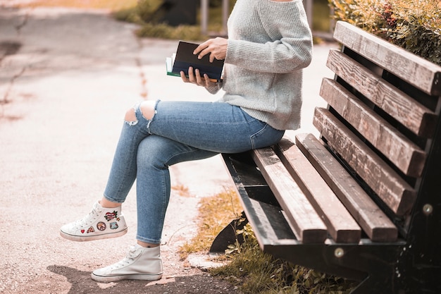 Woman holding volume and sitting on bench